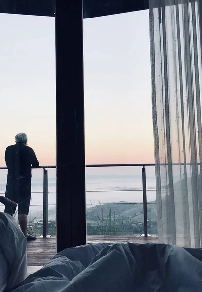 Yaşlı bir adam sundurma duran ve sis gündoğumu sırasında etkileyici. Yatak odasından bir fotoğraf çekmek. Vintage tarzı.