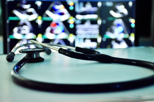 Beyaz masaya bir stetoskop odaklanmak, arka plan bulanık ekokardiyogram (haert ultrason) ekran. Koyu tonu uygulanır.