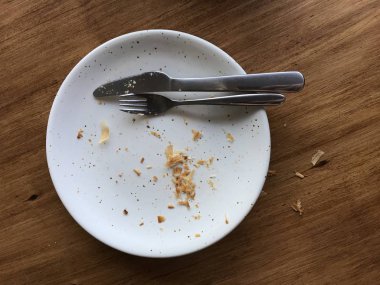 Çatal-bıçak ile boş çanak. Beyaz bir çanak Içinde okuma kırıntı var.