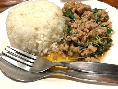 Kıymalı domuz eti ve çatal bıçak takımı ile beyaz çanak cam erişte fesleğen ile pirinç odaklanın.