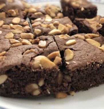 Beyaz çanak üzerinde brownie yatay çizgi merkezinde odaklanın. Kaju fıstığı ile üstüne Closeup nefis brownie.
