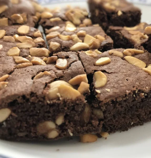 Beyaz çanak üzerinde brownie yatay çizgi merkezinde odaklanın. Kaju fıstığı ile üstüne Closeup nefis brownie.
