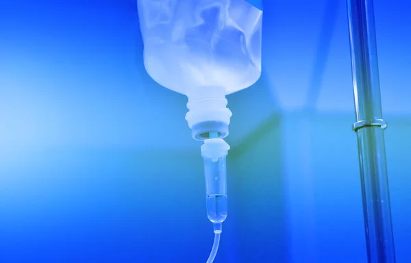 盐水溶液袋用杆子挂 袋子与静脉注射 套连接是给病人的 应用蓝色色调渐变 纹理有复制空间 图库照片