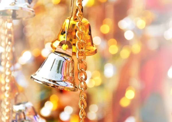 Focus copper gold and silver bells hang on gold chain, there is bokeh blurred background. These are decorated in celebration, carnival, festival or Christmas. There is copy space for texture on right.