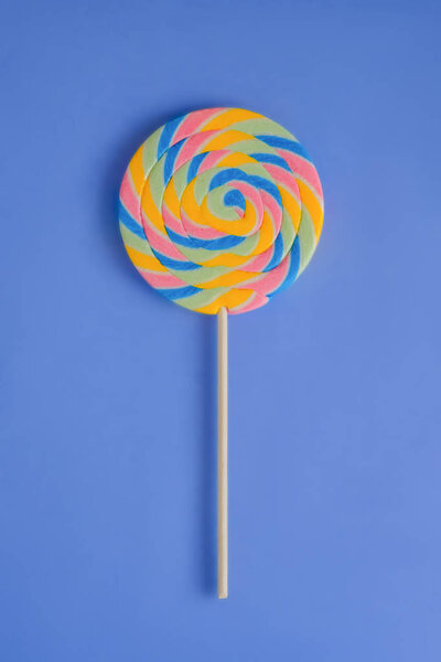 A multicolored round lollipop on a bright blue background. 