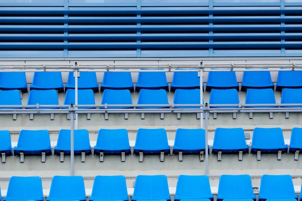 Empty plastic chairs in the stands of the stadium. Many empty seats for spectators in the stands.