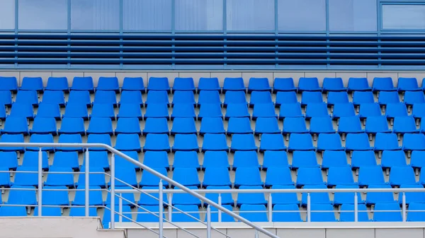 Empty plastic chairs in the stands of the stadium. Many empty seats for spectators in the stands.