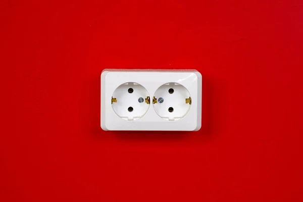 Enchufe en la pared roja. Copiar espacio. El concepto de ahorro de energía. Toma eléctrica blanca en la pared roja. Primer plano. —  Fotos de Stock