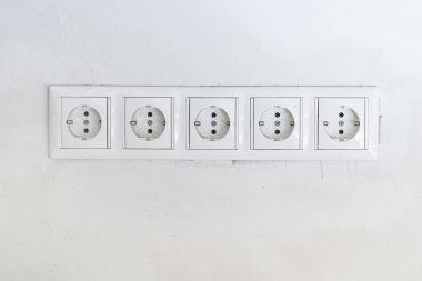 Arka plan olarak beyaz duvarda çerçeveli beş beyaz Güç soketi