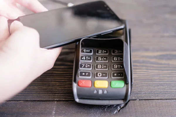 Terminal POS, Maszyna płatnicza z telefonem komórkowym na tle sklepu. Płatność bezdotykowa za pomocą technologii NFC — Zdjęcie stockowe