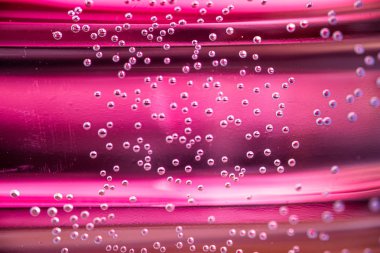 Küçük hava kabarcıkları odak ve unfocus pembe arka plan ile suda asılı. Kabarcıklar makro çekim yakın çekim. 