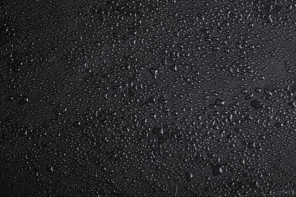 Dark gray black slate background with water drops or natural stone texture.