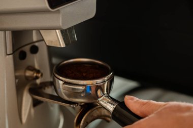 Kahve öğüten kahveciye yakın çekim. Kahve makinesiyle kahve yapan profesyonel bir barista. Sıcak içki konsepti. Renkli resim