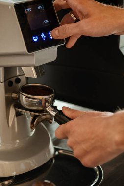 Kahve öğüten kahveciye yakın çekim. Kahve makinesiyle kahve yapan profesyonel bir barista. Sıcak içki konsepti. Renkli resim