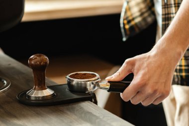 Barista kahveyi kurcalayarak ütülüyor. Kahve makinesiyle kahve yapan profesyonel bir barista. Sıcak içki konsepti. Renkli resim