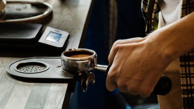 Barista kahveyi kurcalayarak ütülüyor. Kahve makinesiyle kahve yapan profesyonel bir barista. Sıcak içki konsepti. Renkli resim