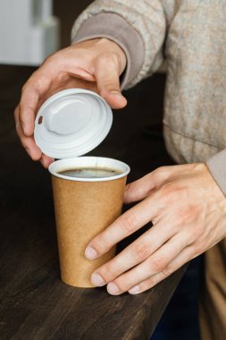 Bir adam kağıt bardakta kahve aldı ve plastik kapakla kapattı. Yemek ve içecek konsepti..