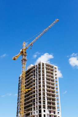 Apartman blokları inşa edilirken bir inşaat alanındaki vinç kulesi. İnşaat halindeki konutların detayları. Metal destekli beton yapı ve geçici ahşap korkuluklar