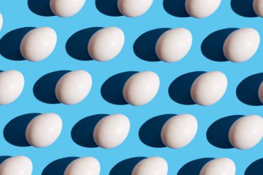 Pastel mavi arka planda yumurtadan yapılmış desen. Asgari gıda konsepti. Moda olmayan şekilli yumurtaların yassılaşması..