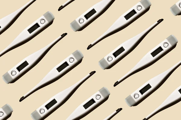 Pastel bej arka planda izole edilmiş elektronik modern termometrelerin deseni. Ateş teşhisi, tıbbi muayene ve sağlık konsepti