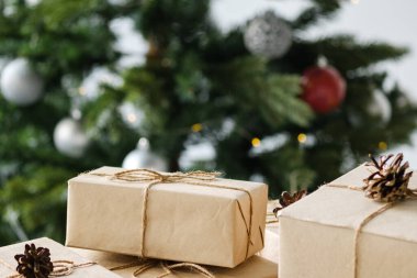 Noel hediyeleri ahşap bir masanın üzerinde süslemeli bir Noel ağacının arka planında. Noel ve Yeni Yıl kavramı.