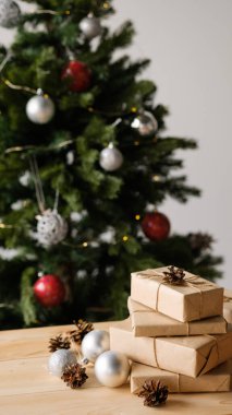 Noel hediyeleri ahşap bir masanın üzerinde süslemeli bir Noel ağacının arka planında. Noel ve Yeni Yıl kavramı.