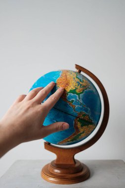 Kız dünya küresindeki bir yeri işaret ediyor. Dünya üzerinde seyahat etmek için bir yer seçer.