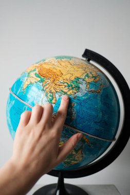 The girl points to a location on the world globe. Chooses a place to travel on the globe. clipart