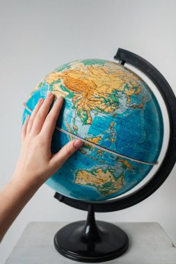 Kazan, Rusya, 29 Şubat 2016: Beyaz arka planda izole edilmiş bir dünya küresine dokunarak kadın eli. Eğitim, bilim, keşif konsepti. Boşluğu kopyala