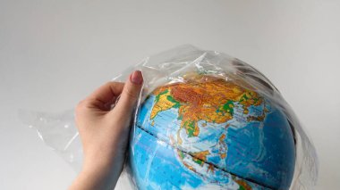 Dünya Çevre Günü konsepti. Bir insan eli yerden plastik bir torba çıkarır. Sosyal reklamlar için formda metne yer var. Plastiğe hayır! Dünyayı kirlilikten koru.