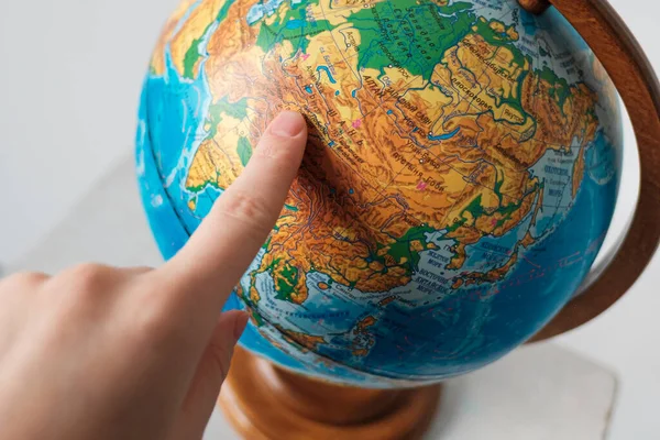 Kız dünya küresindeki bir yeri işaret ediyor. Dünya üzerinde seyahat etmek için bir yer seçer.