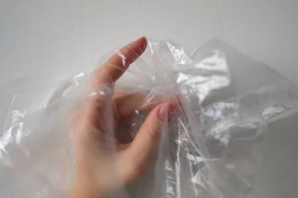 プラスチックバッグの後ろに手をトリミング 白い色の半透明のビニール袋にしわの表面に触れる匿名の人の手のシルエット 選択的焦点 — ストック写真
