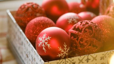 Kutuda kırmızı Noel oyuncakları, Noel ağacı süsleme hazırlığı. İçinde Noel ışıkları ve süslemeleri olan bir Noel kartı. Seçici odak.