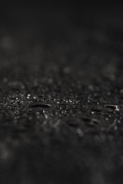 Su damlaları ya da doğal taş dokusu olan koyu gri bir arkaplan. Yakın çekim için kara tahta. Siyah arkaplanda su damlaları var.