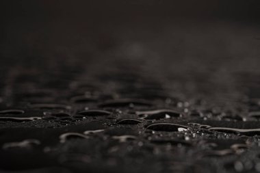 Su damlaları ya da doğal taş dokusu olan koyu gri bir arkaplan. Yakın çekim için kara tahta. Siyah arkaplanda su damlaları var.