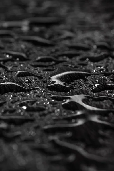 Dark gray black slate background with water drops or natural stone texture. Black board for serving close-up. Drops of water close-up on a black background