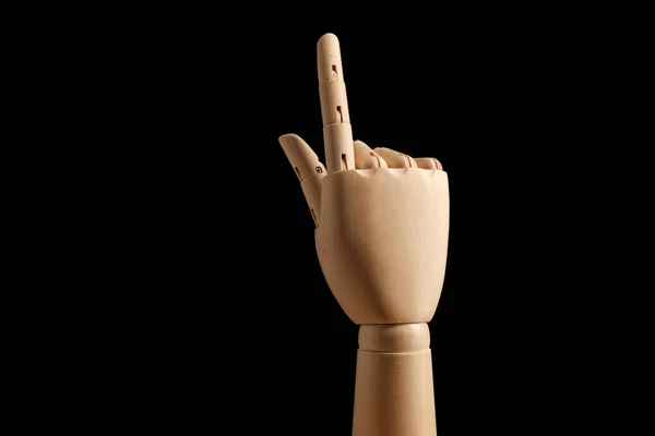 Wooden hand of mannequin for drawing indicates the direction of the index finger on a black background. Learning to count - one. Art model for drawing. Part of the body - hand, brush. Swipe up