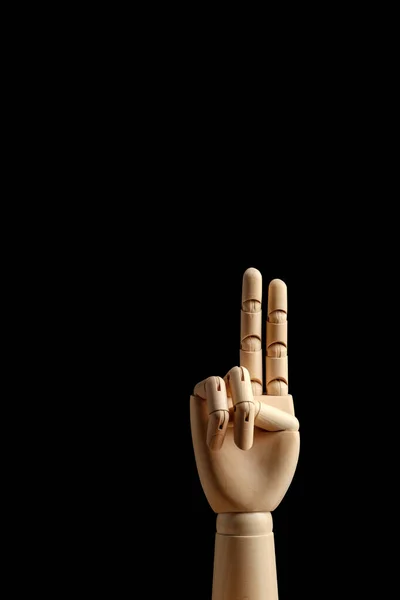Wooden hand of mannequin for drawing shows two fingers on a black background. Learning to count - two. Side view. Art model for drawing. Part of the body - hand, brush.