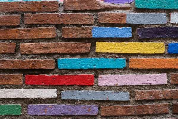 Wall with a bricks painted into blue,yellow, red,lila,green colours