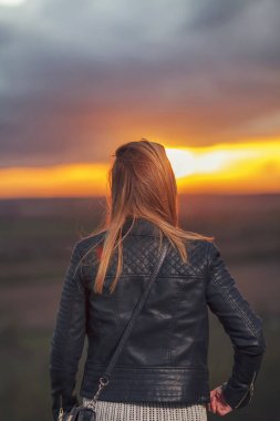 Gün batımında tek başına güneşi izleyen genç kadın.