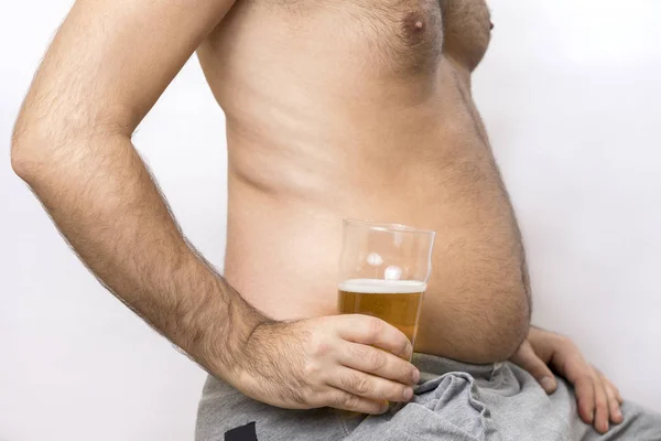 Man with a fat belly holds a glass of beer — Stock Photo, Image