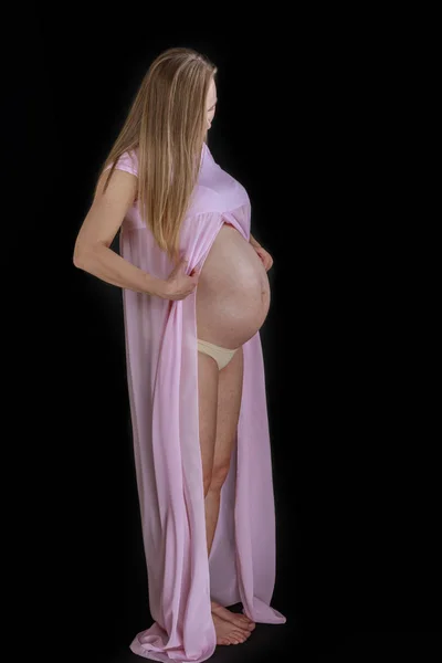 Portré a fiatal gyönyörű terhes nő rózsaszín ruhában a Blac — Stock Fotó