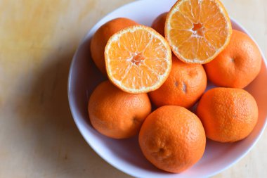 Beyaz ahşap masada olgun portakal rengi mandalinalar.