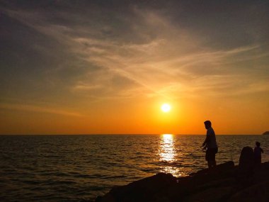 Sillhouette beach goers Tanjung Aru beach, Kota Kinabalu, Sabah üzerinde güneşin tadını bir demet.