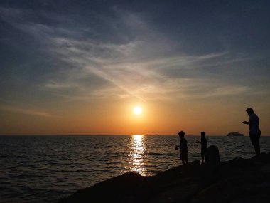 Sillhouette beach goers Tanjung Aru beach, Kota Kinabalu, Sabah üzerinde güneşin tadını bir demet.