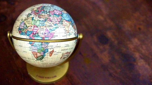 世界の地図とビンテージの世界モデルのショットを背景として木製のテーブルの上を閉じます 選択したフォーカス — ストック写真