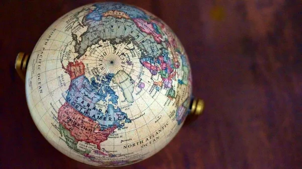 世界の地図とビンテージの世界モデルのショットを背景として木製のテーブルの上を閉じます 選択したフォーカス — ストック写真