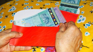 Rm100, Rm50 notlar, Malezya para kırmızı paket para birimiyle holding kadınlar eller. Seçilen odak. Yakın çekim.