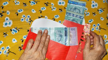 Rm100, Rm50 notlar, Malezya para kırmızı paket para birimiyle holding kadınlar eller. Seçilen odak. Yakın çekim.