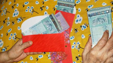 Rm100, Rm50 notlar, Malezya para kırmızı paket para birimiyle holding kadınlar eller. Seçilen odak. Yakın çekim.